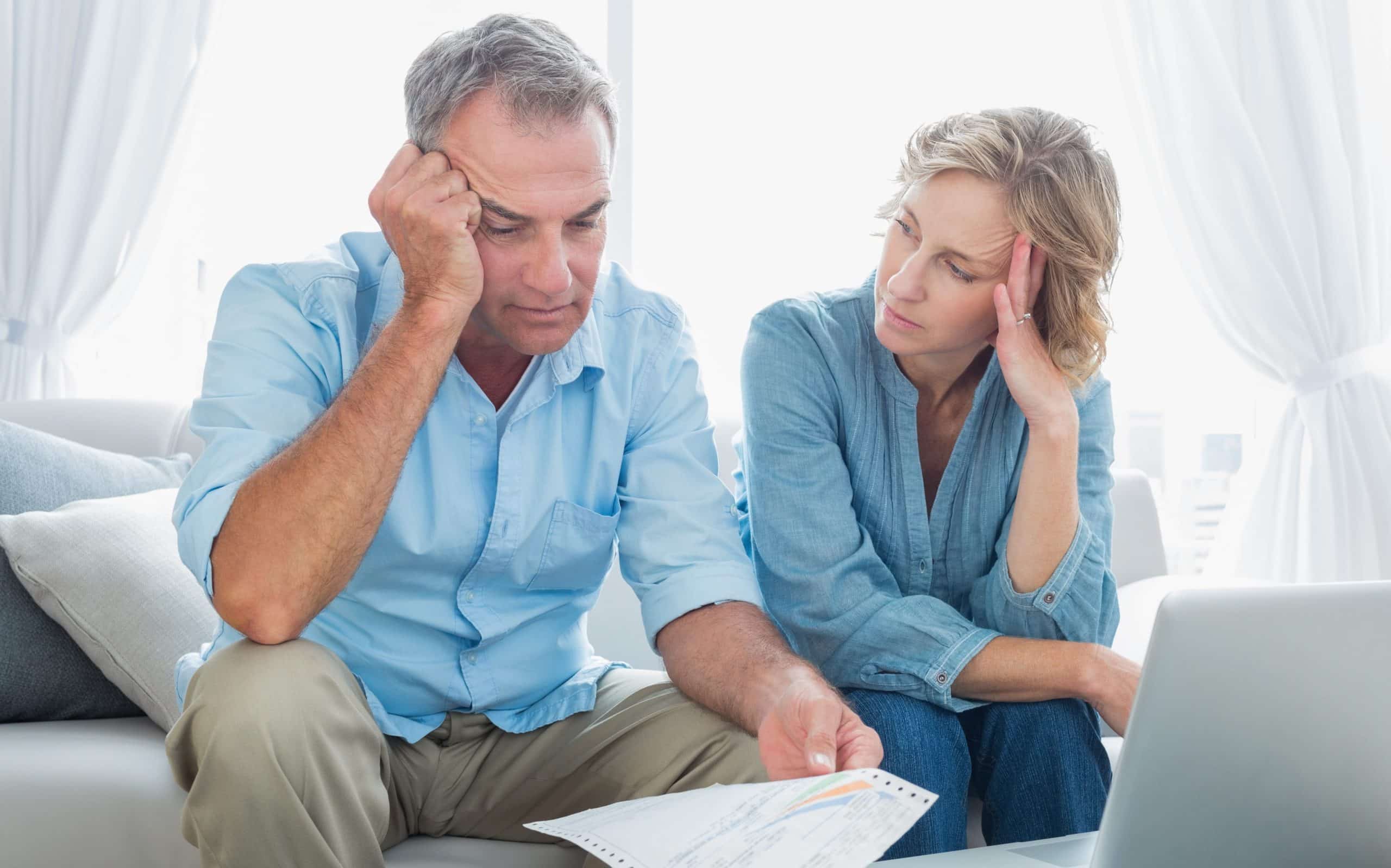 Couple sitting on couch looking at medical bills.